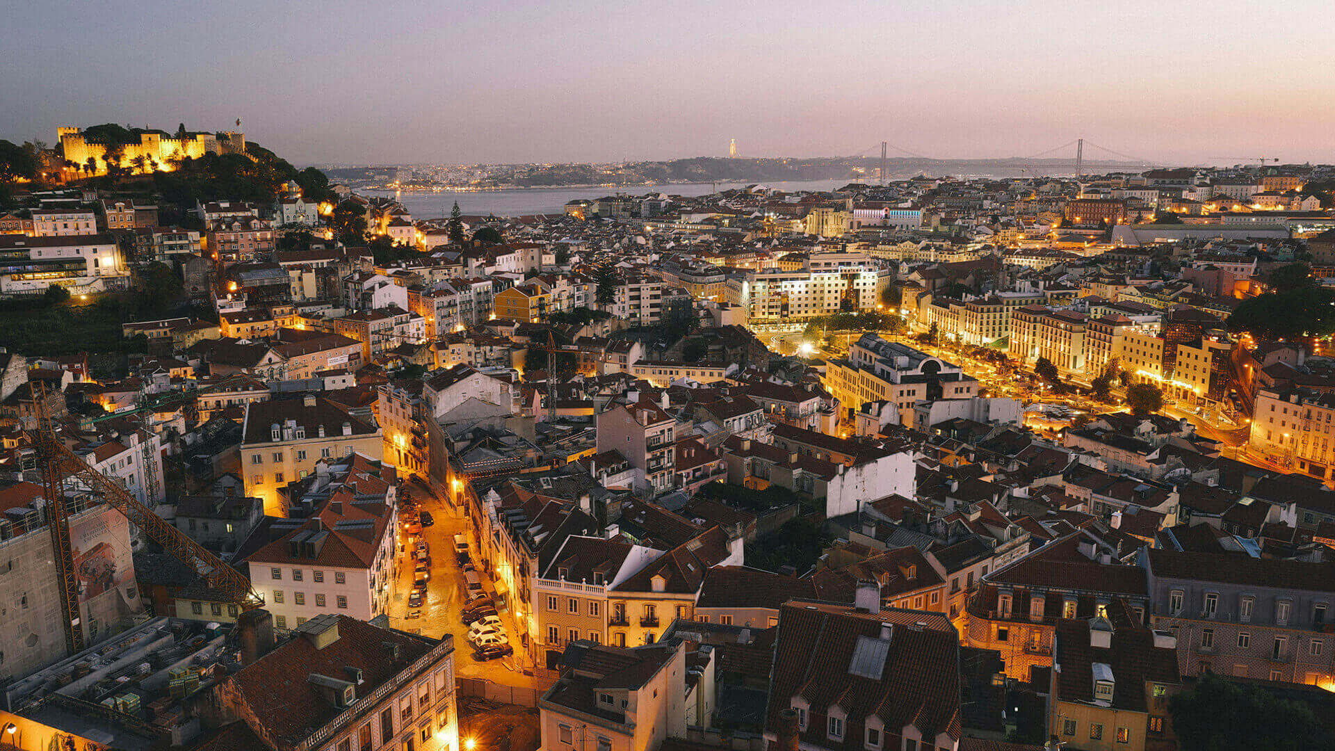 Lisboa vista de cima à noite, com a ponte 25 de Abril e o Cristo-Rei ao fundo