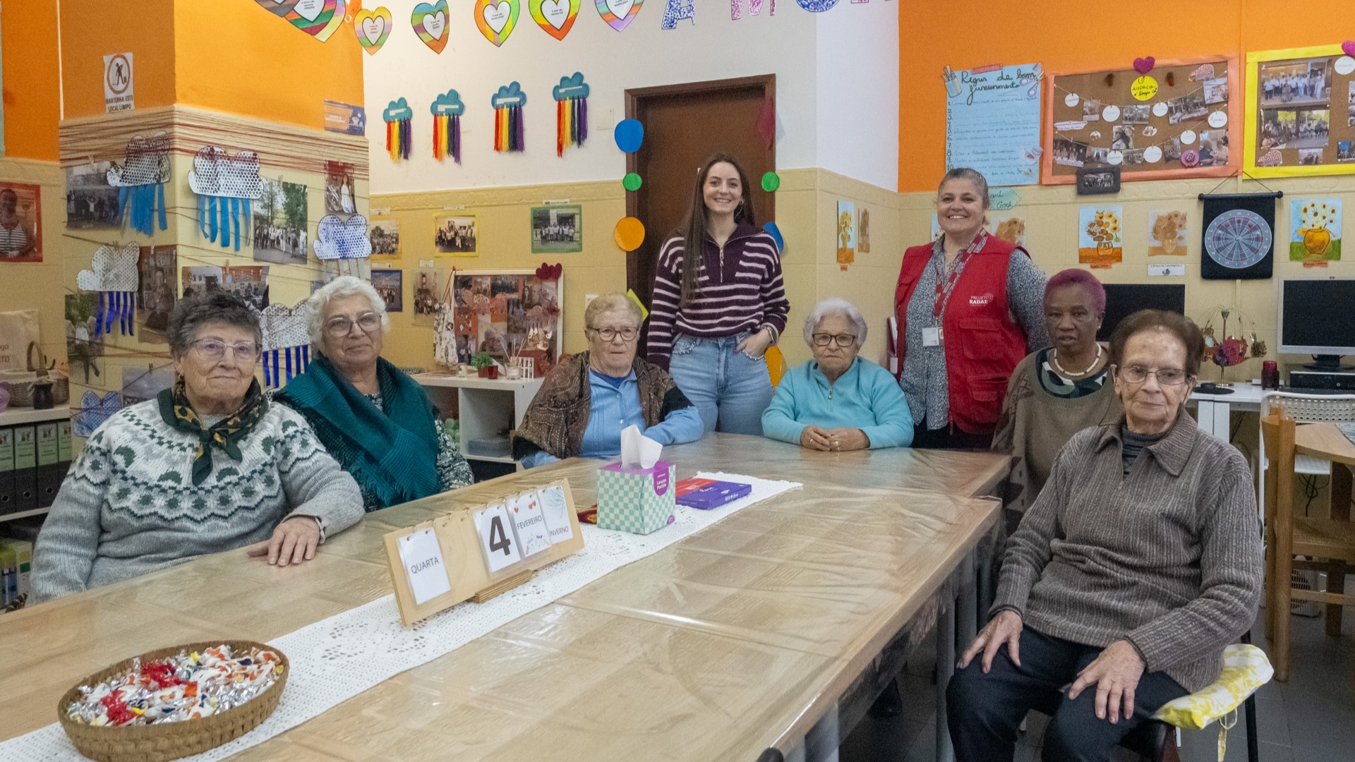 Inês Neves, voluntária do Radar e séniores sentado à mesa no interior do Espaço AMI Olaias