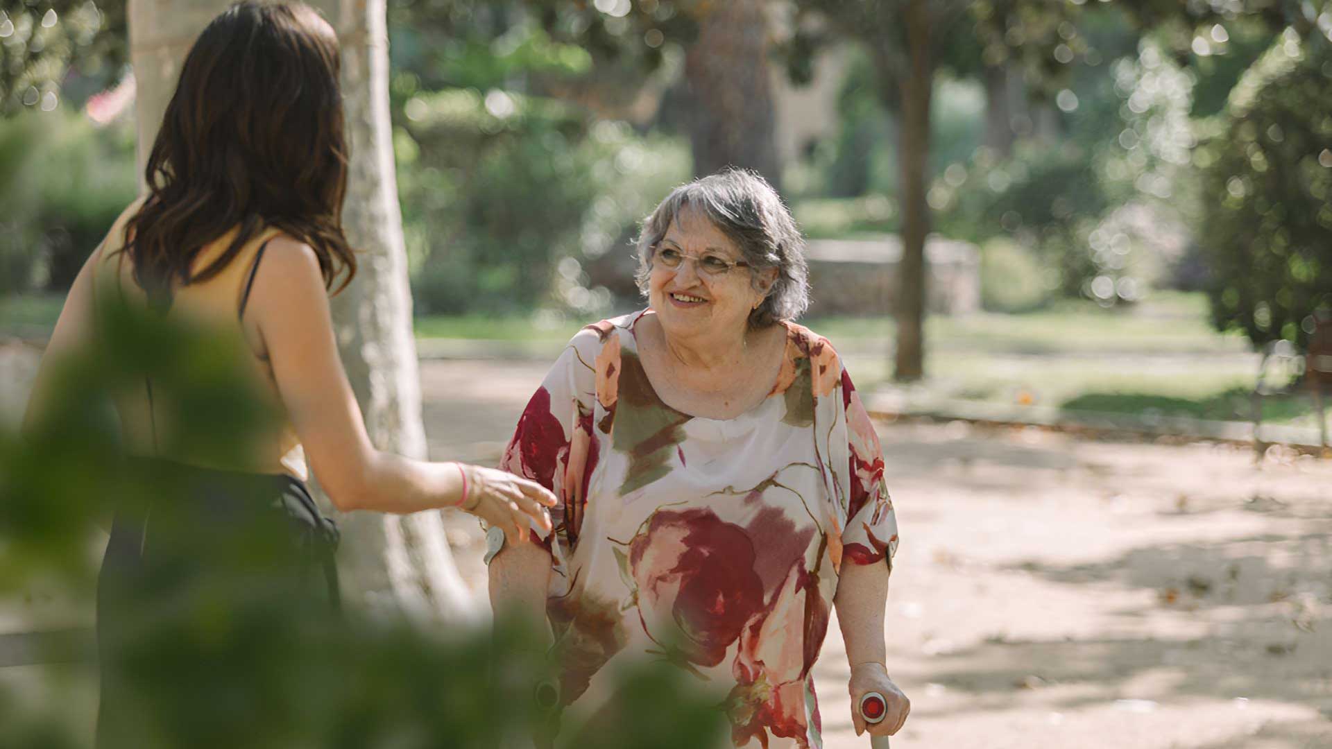 Idosa com canadiana sorri para mulher mais nova